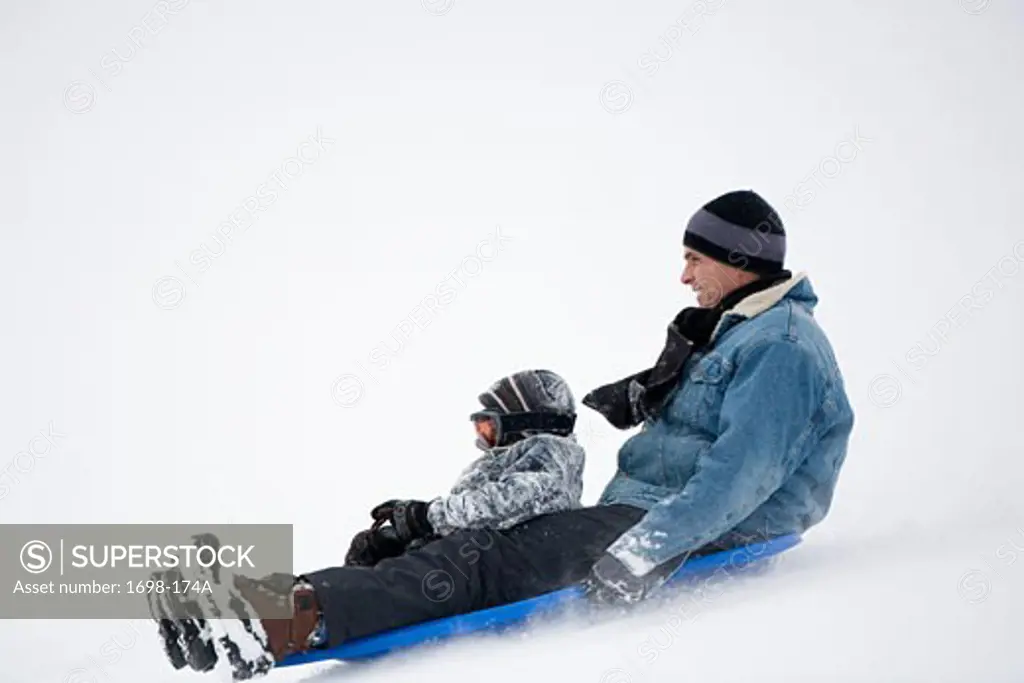 Mature man and his son sledding