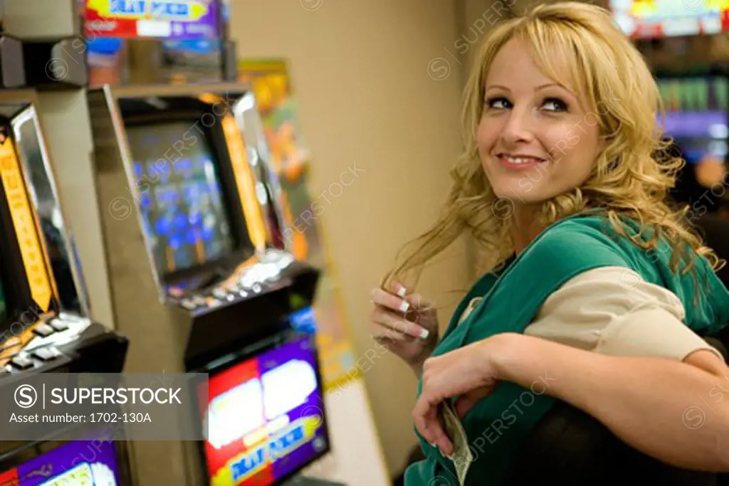 Young woman sitting in front of a slot machine and smiling in a casino