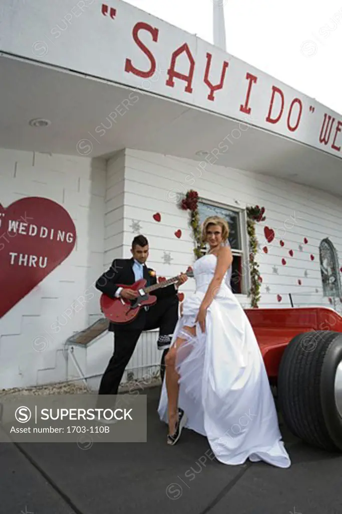 Bride and groom standing beside a drive-thru wedding chapel