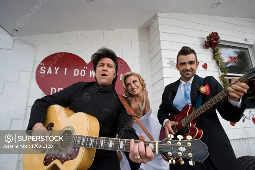 Two men playing guitars with a bride at a drive-thru wedding chapel