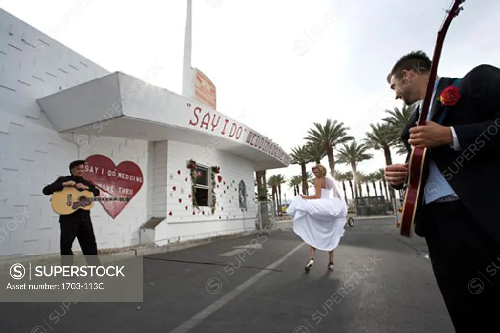 Rear view of a bride and two men with guitars at a drive-thru wedding chapel