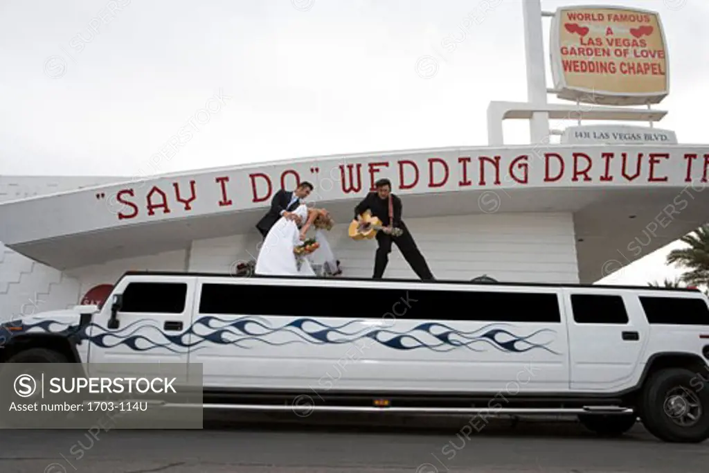 Bride and groom dancing on a limousine with a mature man at a drive-thru wedding chapel
