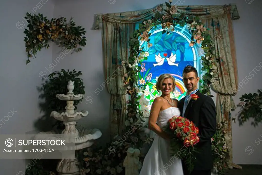 Bride and groom standing in front of a stained glass window