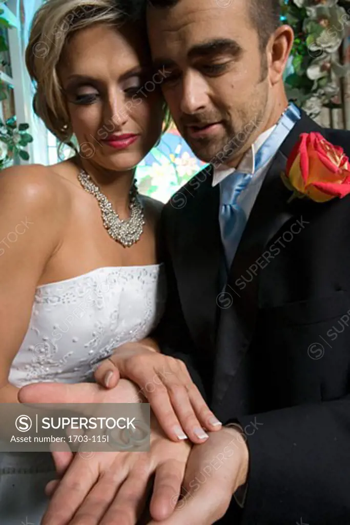 Groom holding rings with his bride
