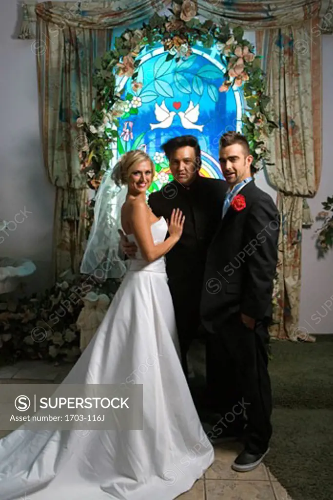Bride and groom standing with a priest