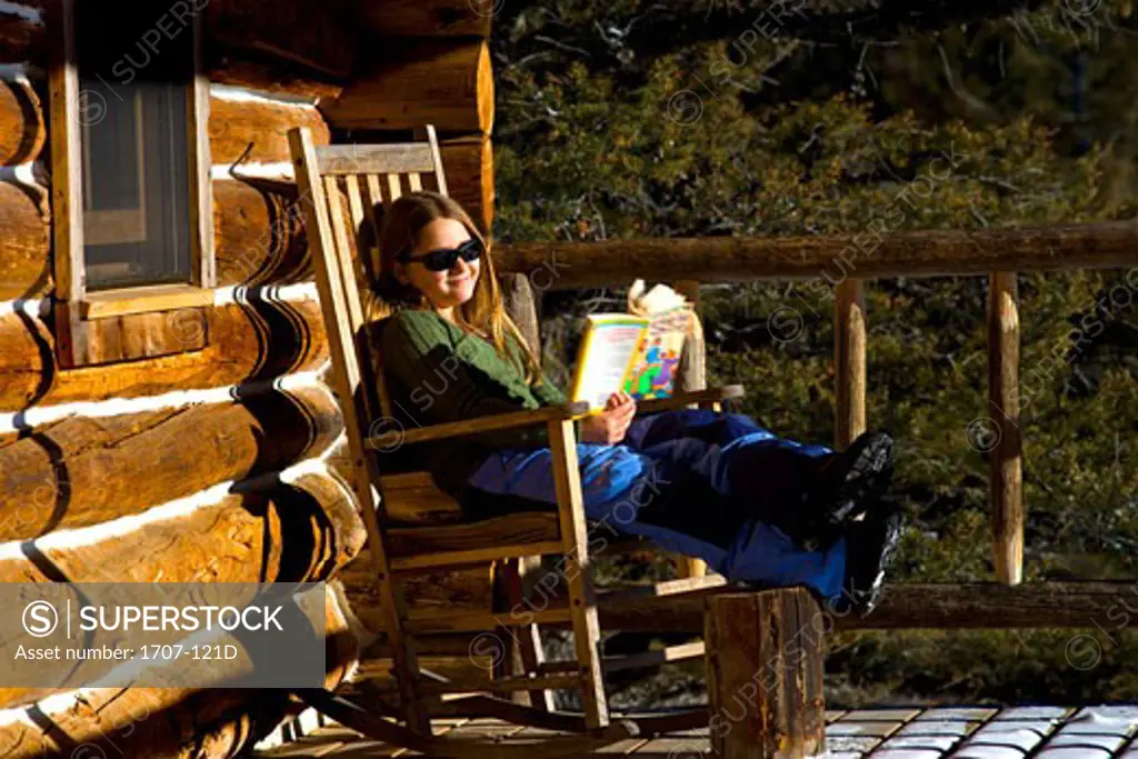Girl sitting in a rocking chair and reading a book
