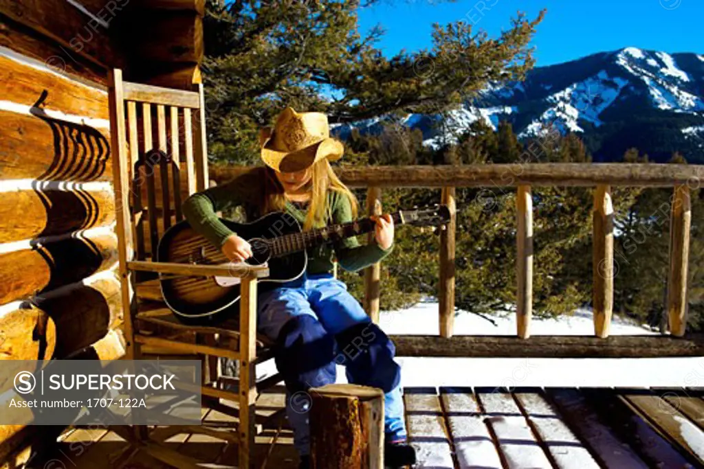 Girl sitting in a rocking chair and playing a guitar
