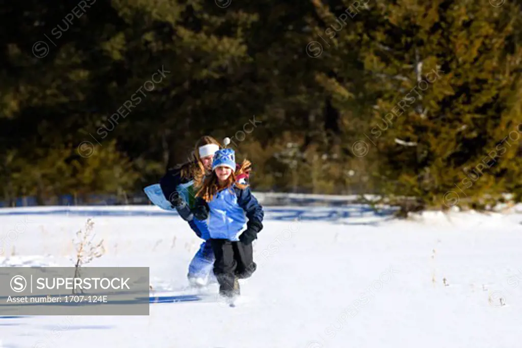 Girl and her sister running in the snow