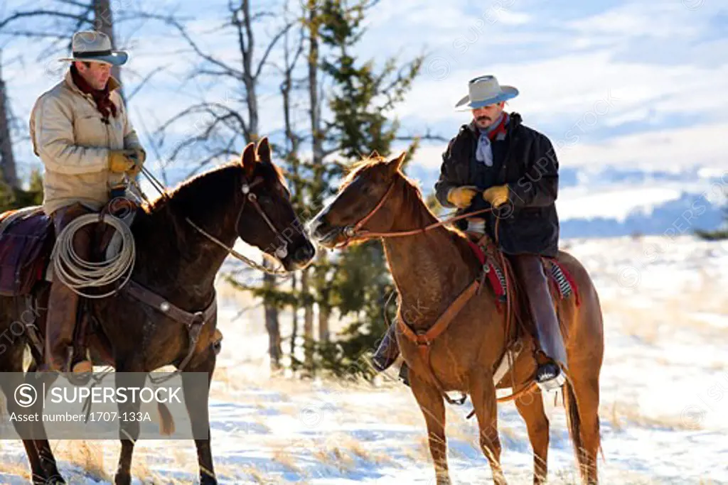 Two men riding horses in a snow covered field