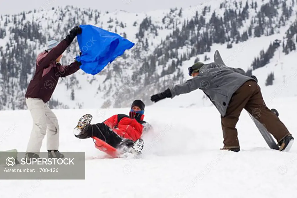 Mid adult man sledding between a mid adult woman and a mid adult man