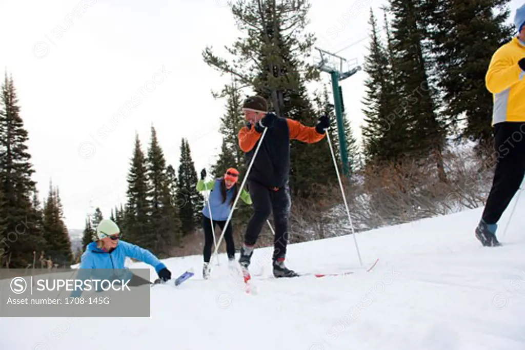 Three people skiing and one person falling