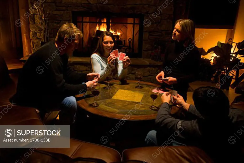 Young couple and a mid adult couple playing cards