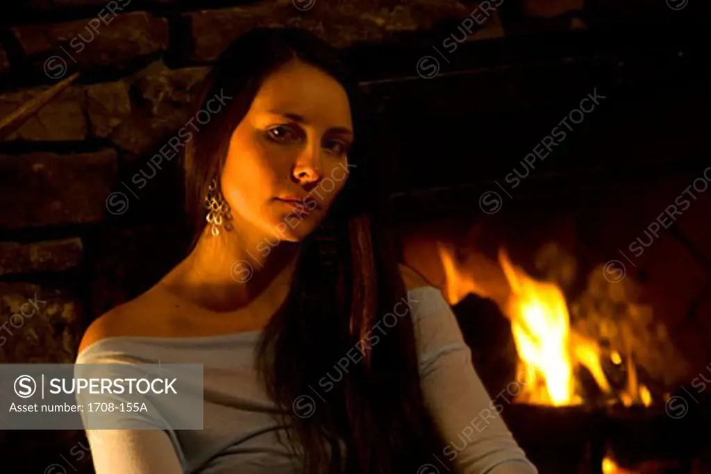 Portrait of a young woman in front of a fireplace
