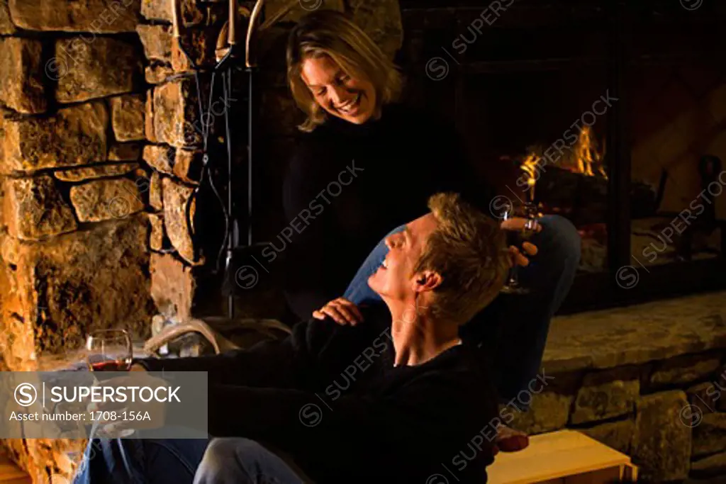 Young man and a mid adult woman sitting in front of a fireplace