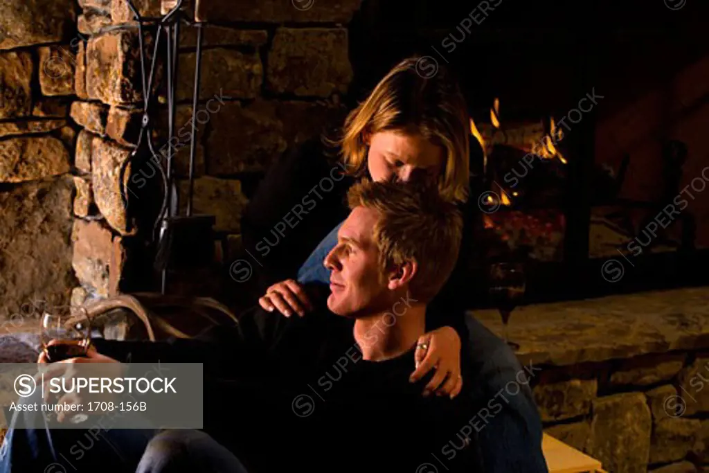 Mid adult woman kissing a young man in front of a fireplace