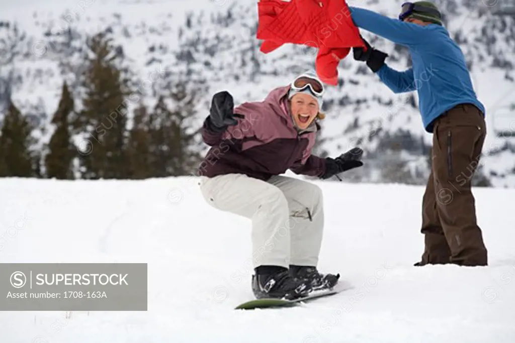 Mid adult woman snowboarding past a mid adult man