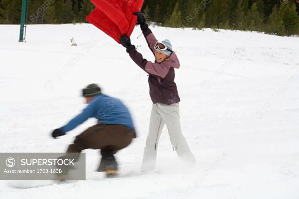 Mid adult man snowboarding past a mid adult woman