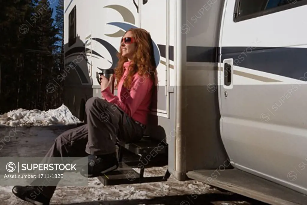 Young woman sitting on the steps of a recreational vehicle