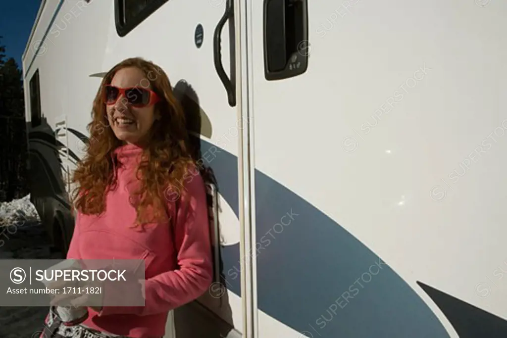 Young woman leaning against a recreational vehicle
