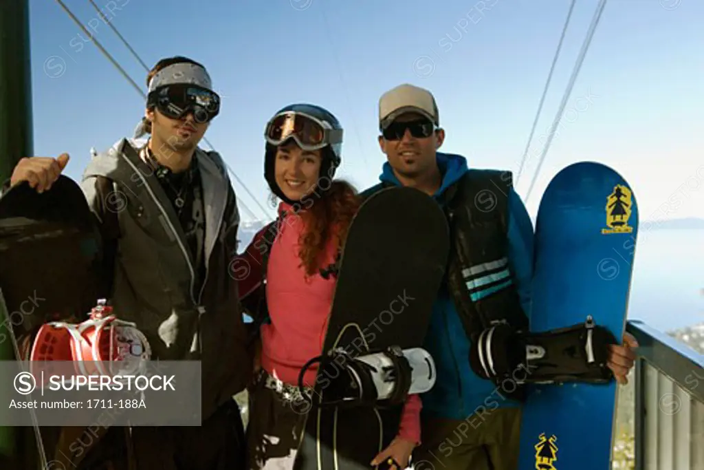 Young man and a young woman standing with a mid adult man and snowboards