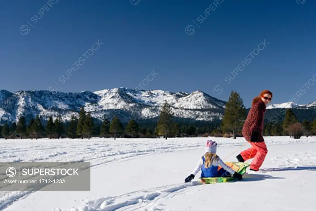 Mature woman pulling her daughter on a sled