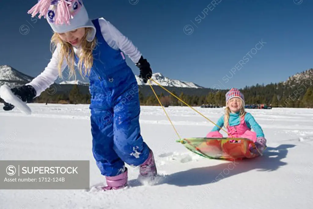 Girl pulling her sister on a sled