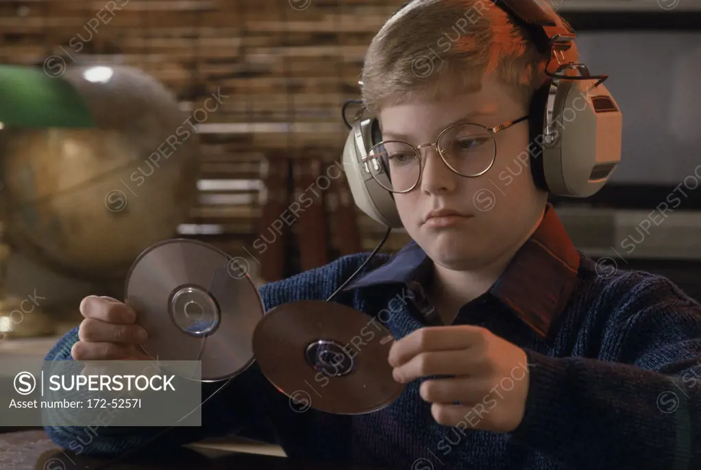 Close-up of a boy listening to music and looking at two CDs
