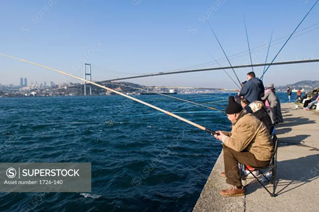 Group of people fishing in the sea near a bridge, Bosphorus Bridge, Bosphorus, Istanbul, Turkey