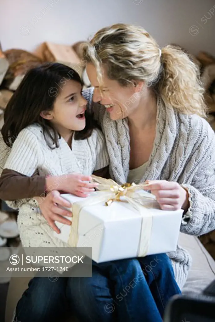 Mid adult woman and her daughter opening a Christmas present