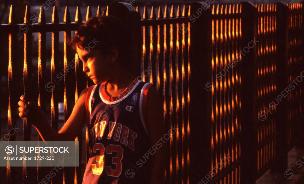 USA, New York State, New York City, Brooklyn Heights, Boy on Brooklyn Promenade looking through fence at sunset