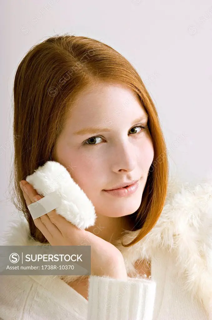 Portrait of a young woman applying face powder