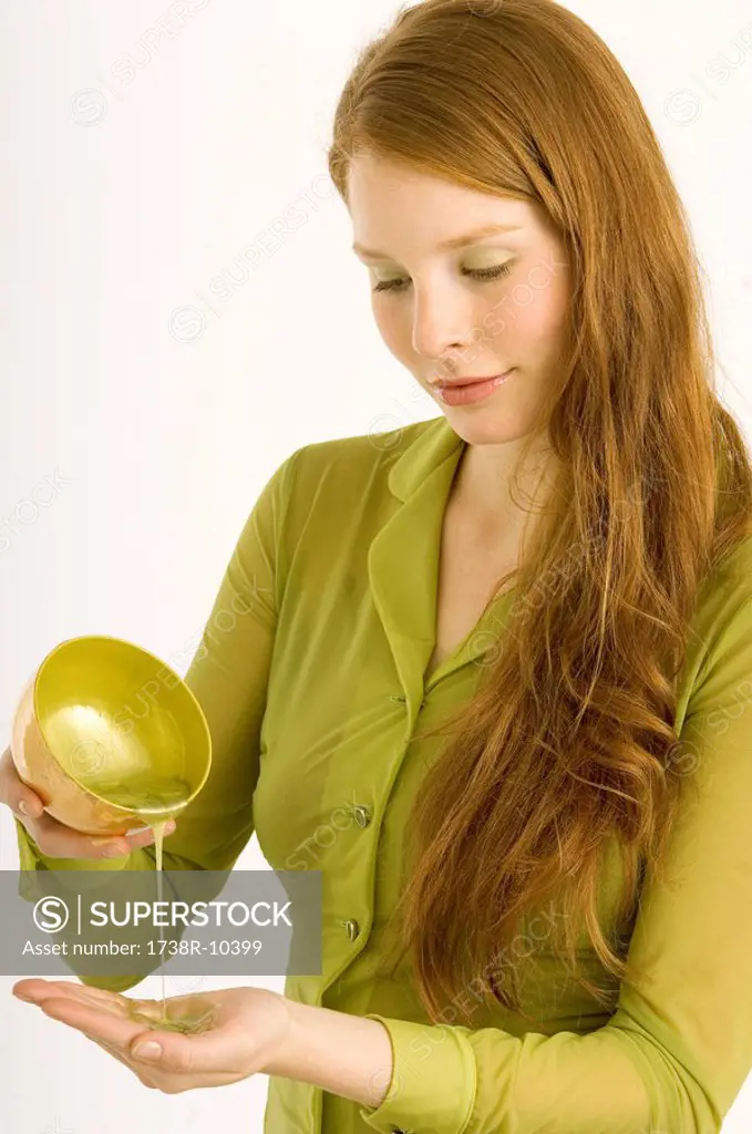 Young woman pouring massage oil on her palm