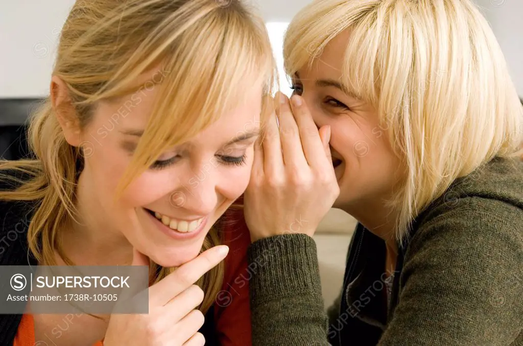Close_up of a young woman whispering to her friend