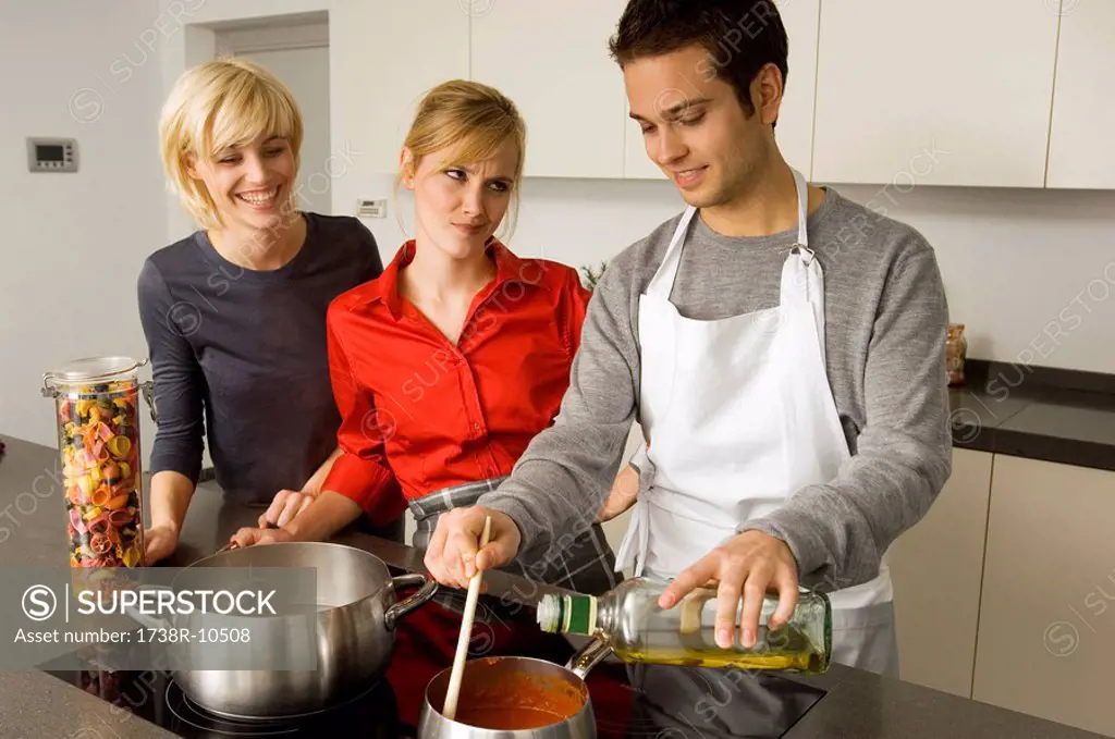 Two young women and a young man preparing food in the kitchen