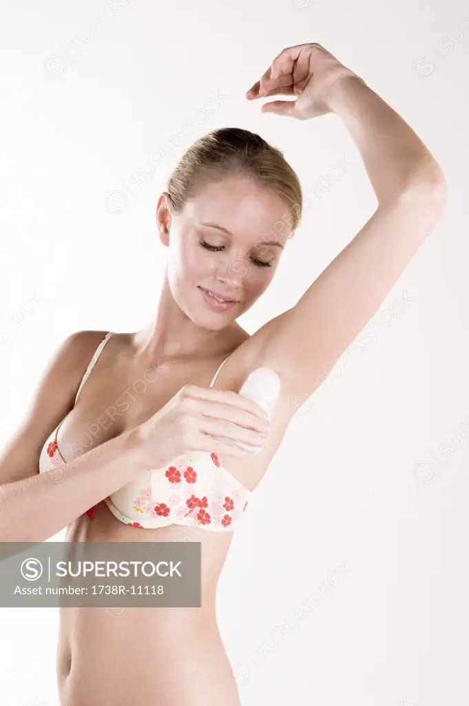Woman applying deodorant under the arm