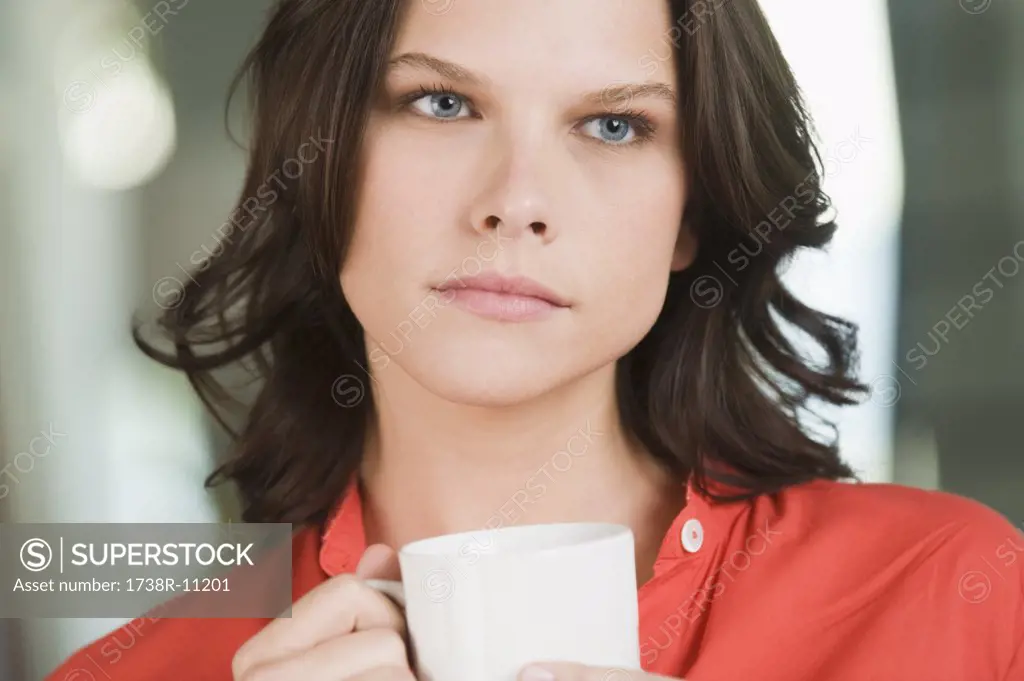 Woman holding a cup of tea and thinking