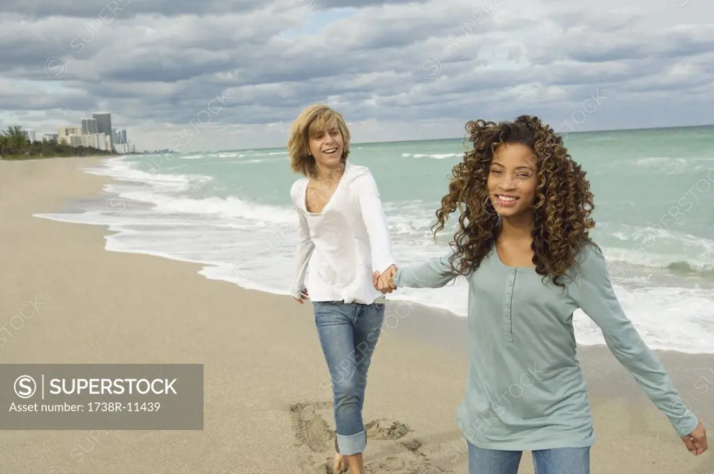 Girl holding hand of a teenage boy on the beach