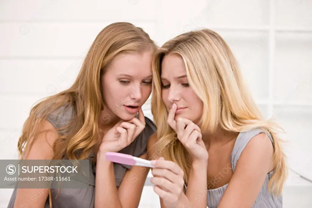 Two women looking at a pregnancy test stick