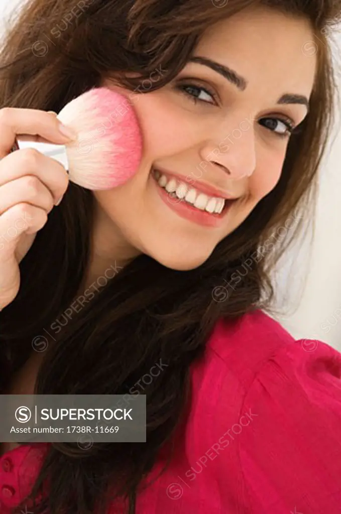 Portrait of a woman applying blusher on her face