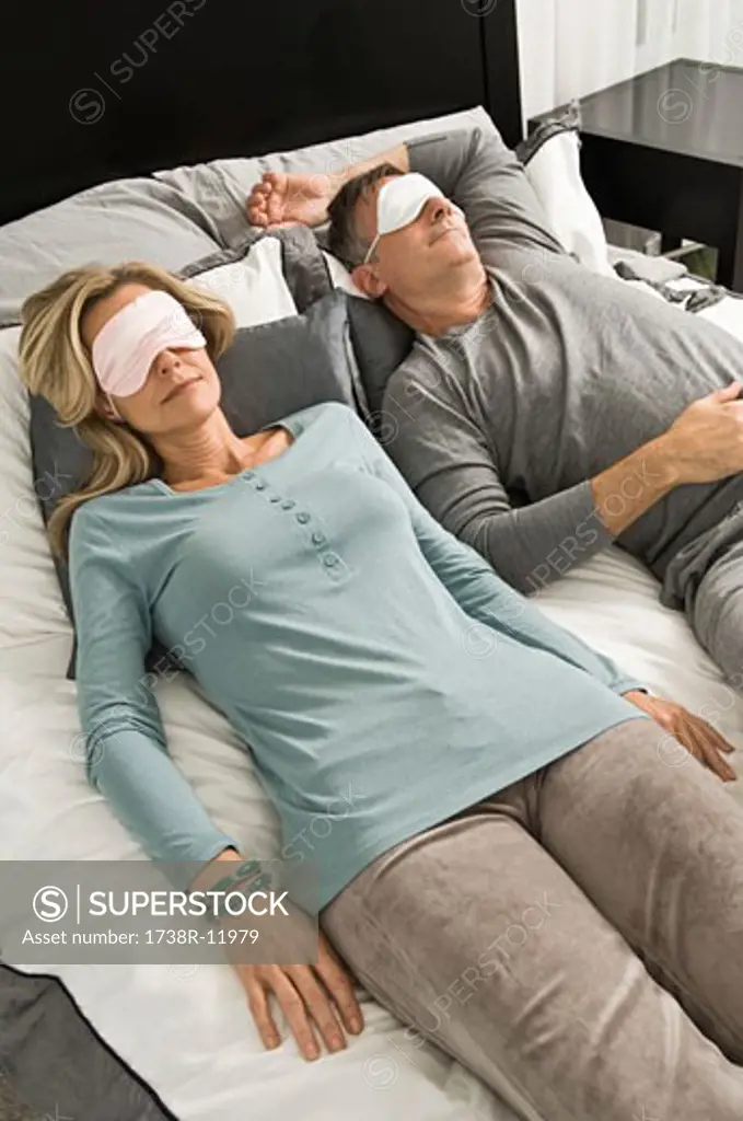 Couple sleeping in bed wearing eye masks