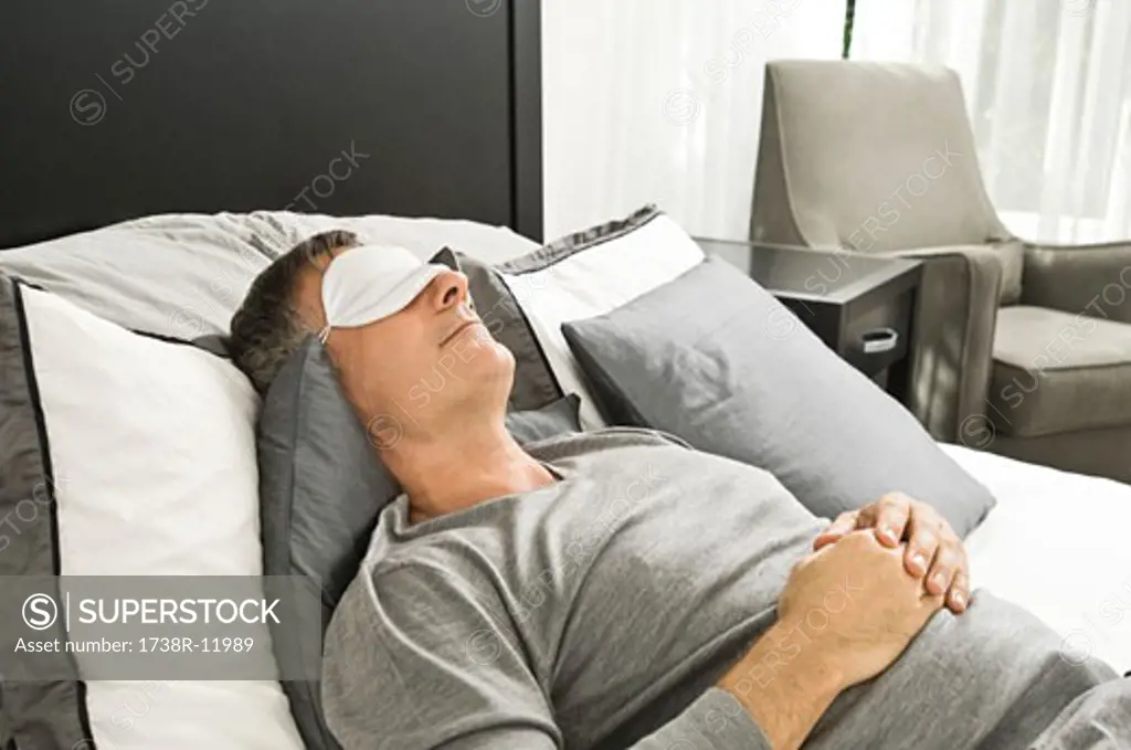 Man sleeping in bed wearing an eye mask