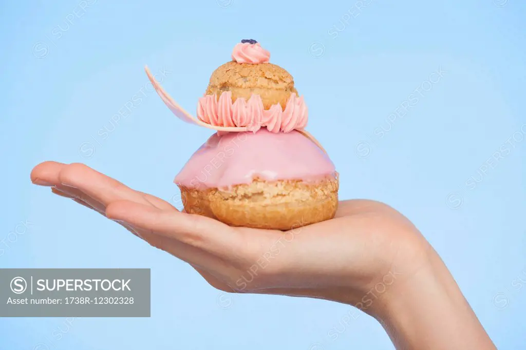 Close-up of a woman's hand holding a french strawberry religieuse