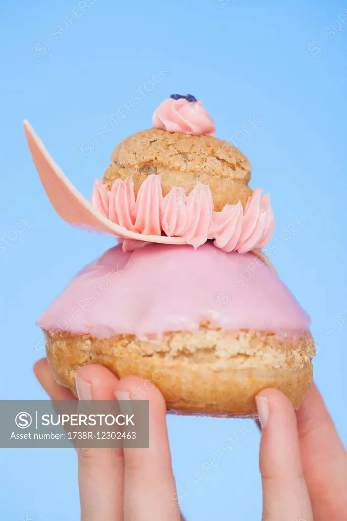 Close-up of a woman's hand holding a french strawberry religieuse