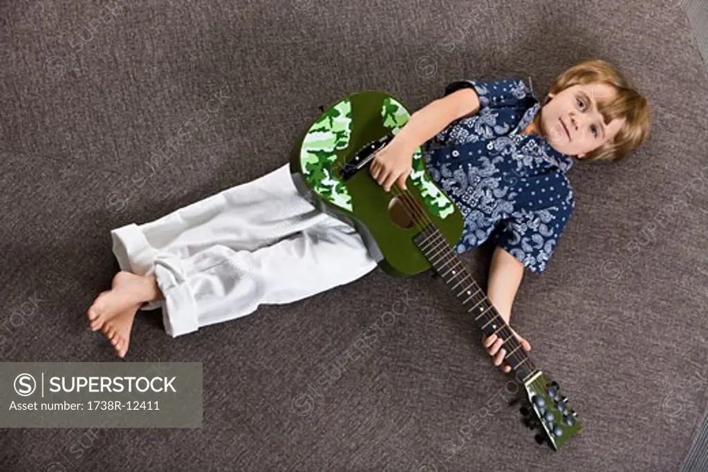 Boy lying on a round table and playing a guitar