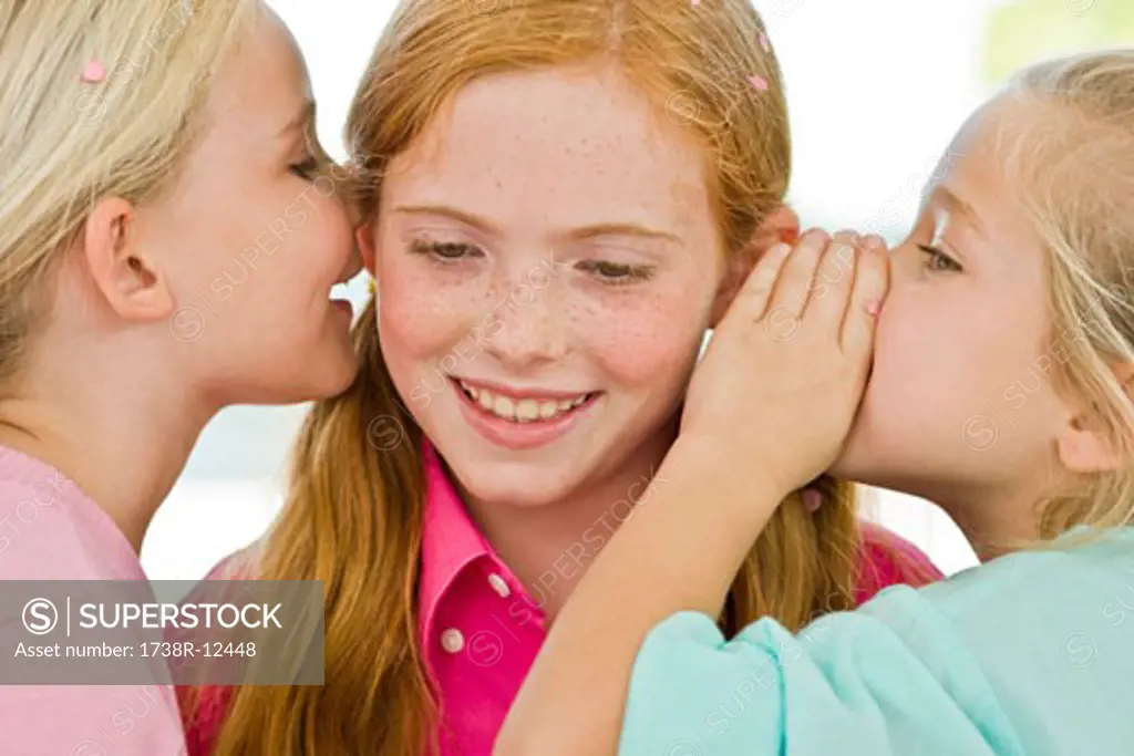 Two girls whispering to another girl