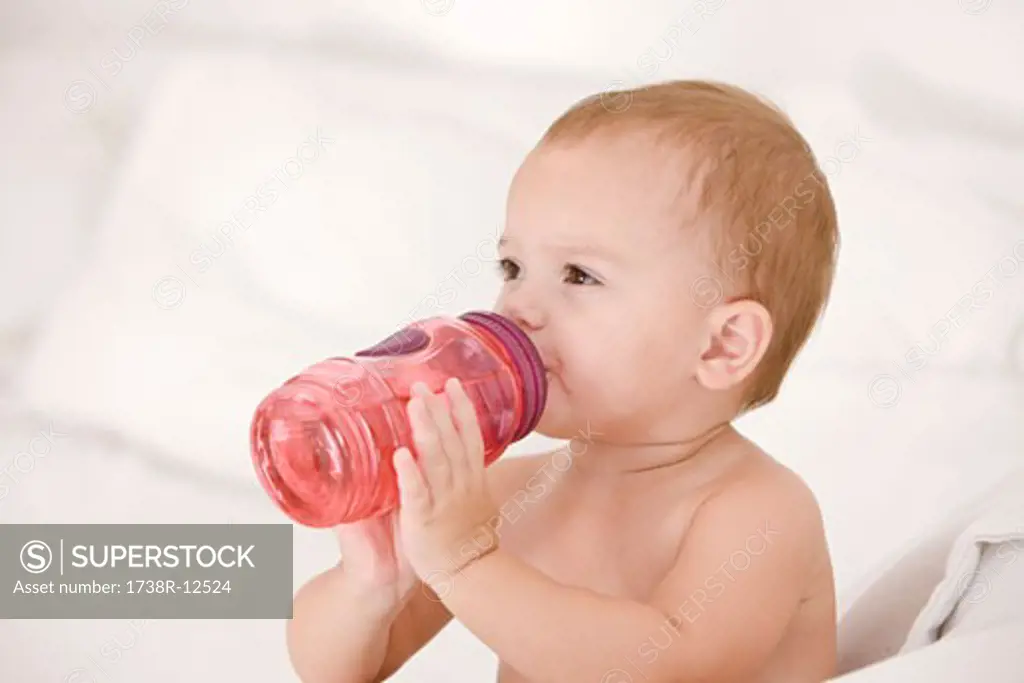 Baby girl drinking water from a baby bottle