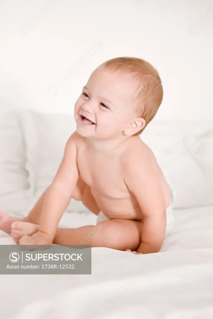Close-up of a baby girl laughing on the bed