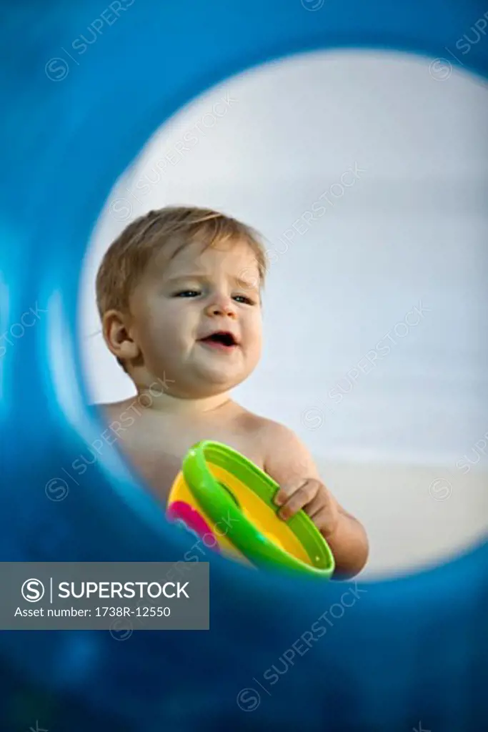 Baby boy playing with a toy viewed through an inflatable ring