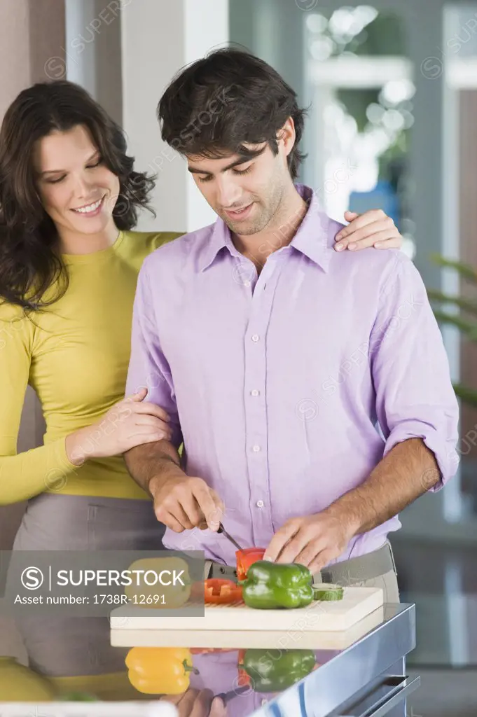 Man cutting bell peppers with a woman standing beside him