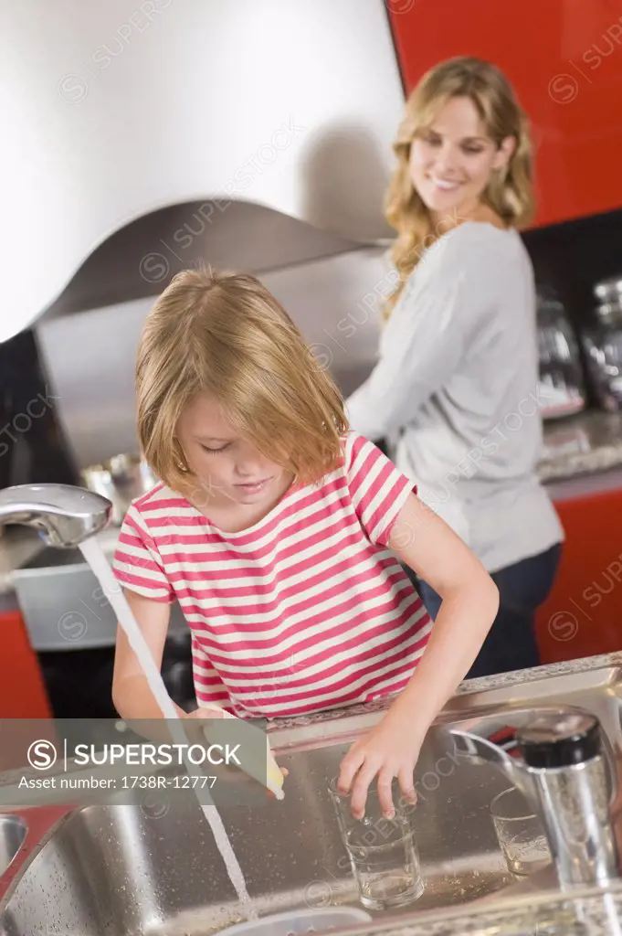 Girl washing glasses in the kitchen